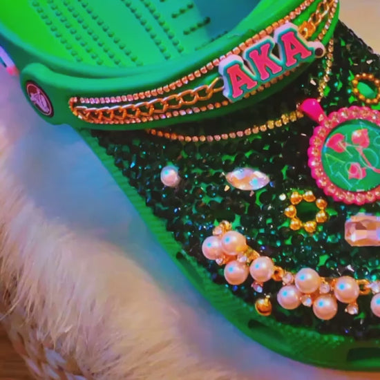 Step into sisterhood with our AKA Sorority Inspired Crocs: vibrant green, sparkling rhinestones, elegant pearls, lavish gold, and chic pink accents. A tribute to unity and style. 💚👡🌟 #SororityPride #Fashion