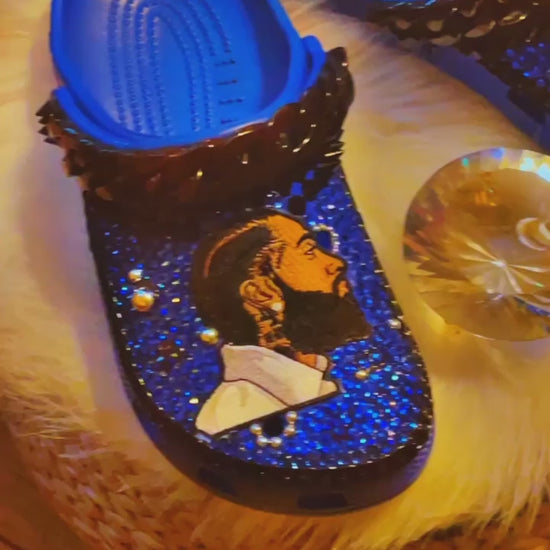 Step into Nipsey Hussle's legacy with our Blue Crocs. Featuring a Nipsey Hussle patch and iconic Jibbitz, these Crocs pay homage to the legendary artist. The sleek blue design and chic black accents add urban style to comfort. 🎵👟🌟 #NipseyHussle #CustomCrocs #FashionFootwear - Video