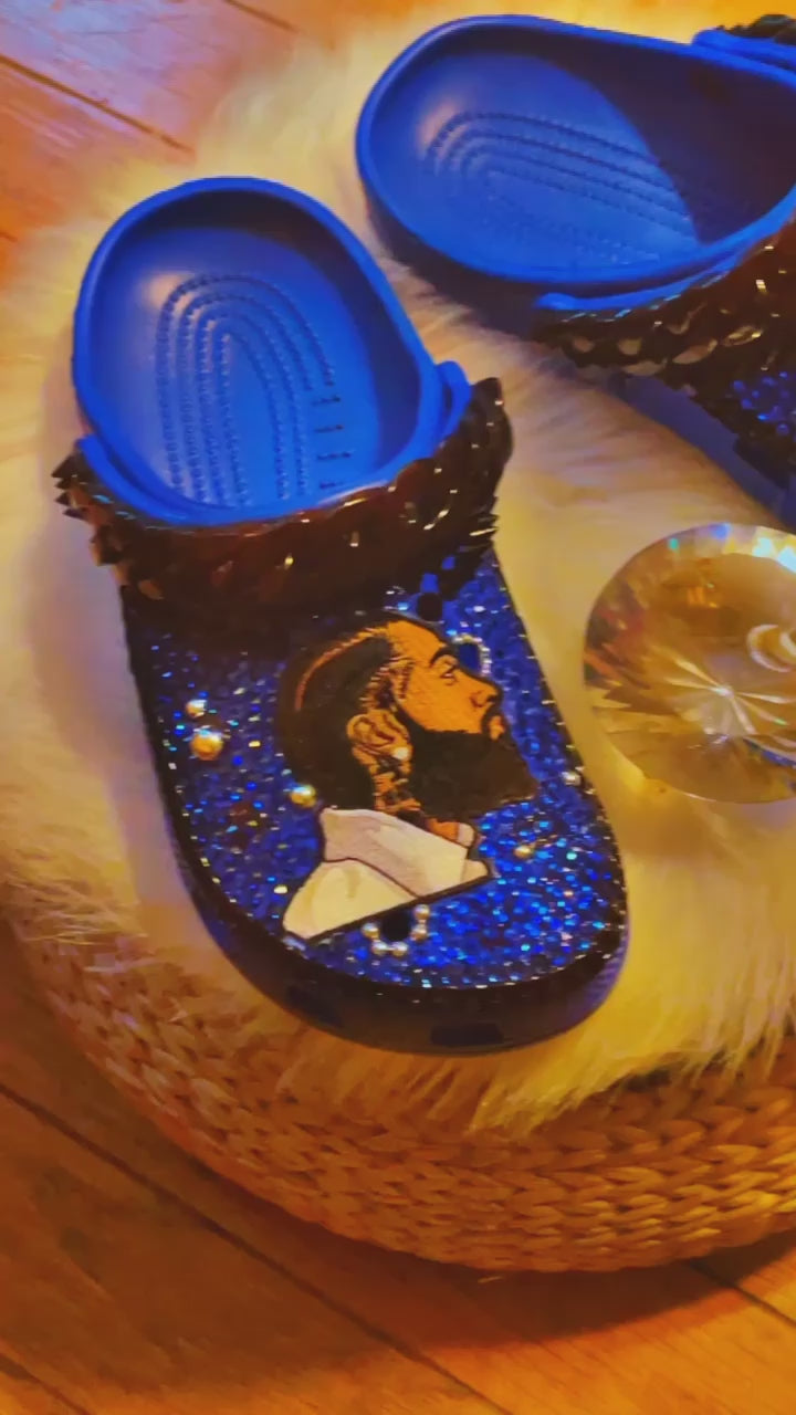 Step into Nipsey Hussle's legacy with our Blue Crocs. Featuring a Nipsey Hussle patch and iconic Jibbitz, these Crocs pay homage to the legendary artist. The sleek blue design and chic black accents add urban style to comfort. 🎵👟🌟 #NipseyHussle #CustomCrocs #FashionFootwear - Video