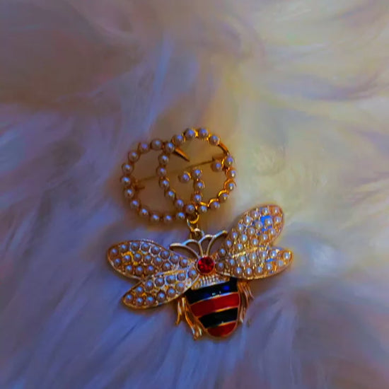 Gold bee brooch featuring a pearl-studded "GG" emblem