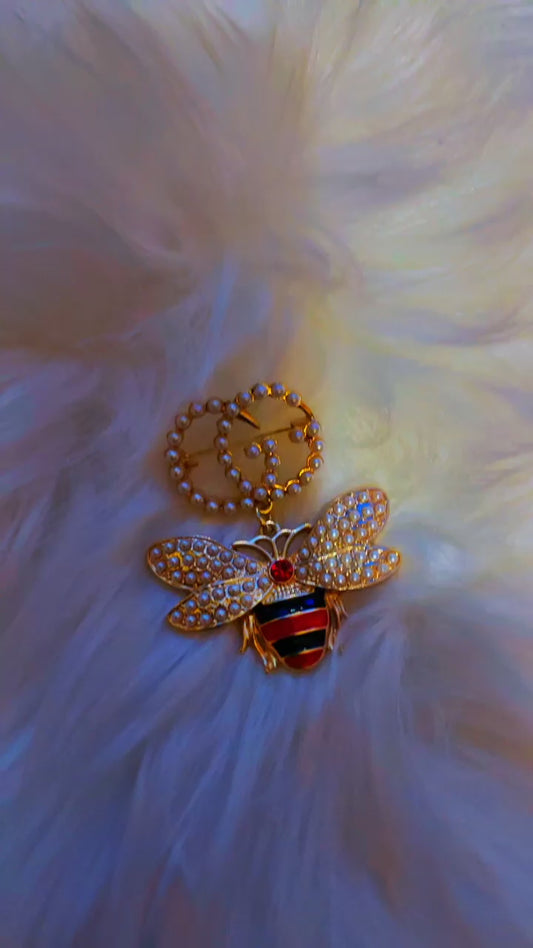 Gold bee brooch featuring a pearl-studded "GG" emblem